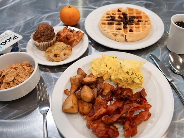 Free hot breakfast spread with eggs, bacon, potatoes, waffles, pastries, and cereal at Coast Calgary University Area Hotel by APA.