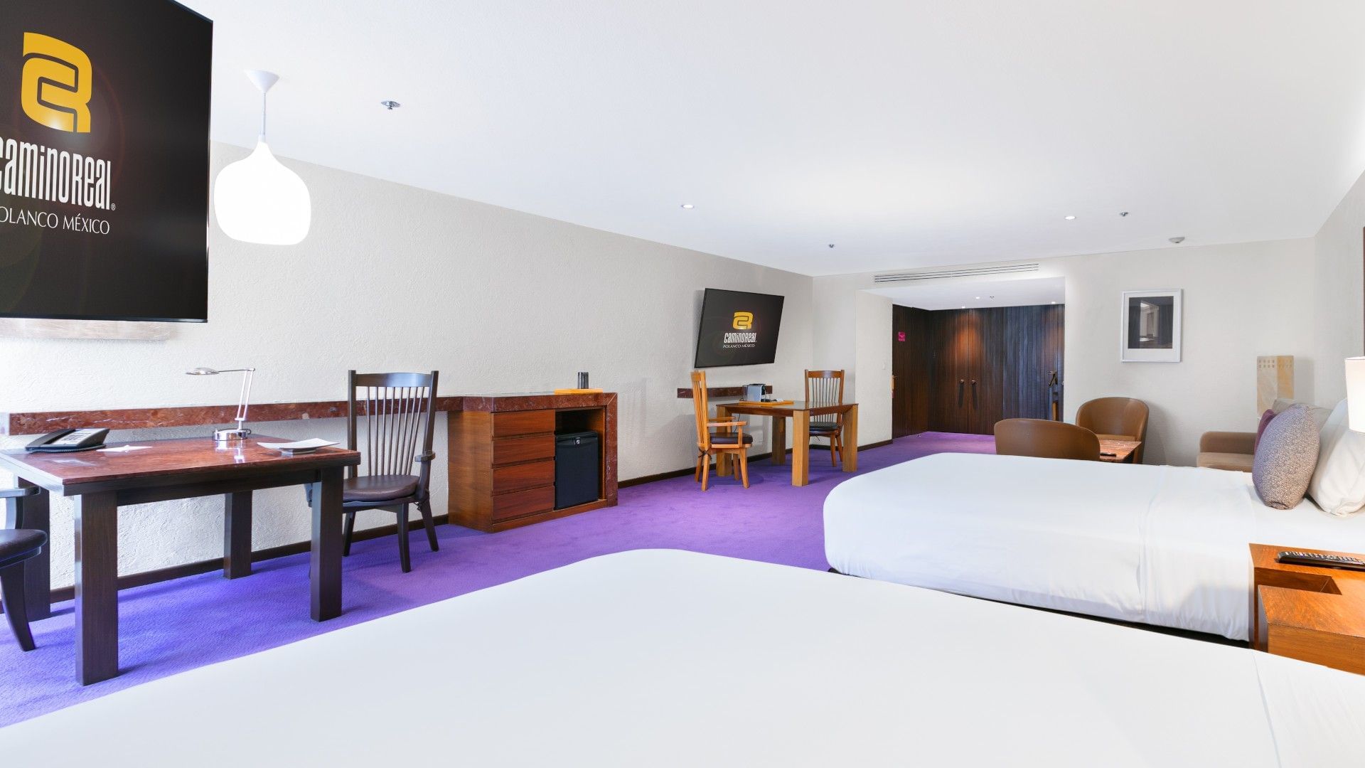 2 Double Junior Suite with a work desk, seating area, and vibrant purple carpeting at Camino Real Polanco Mexico