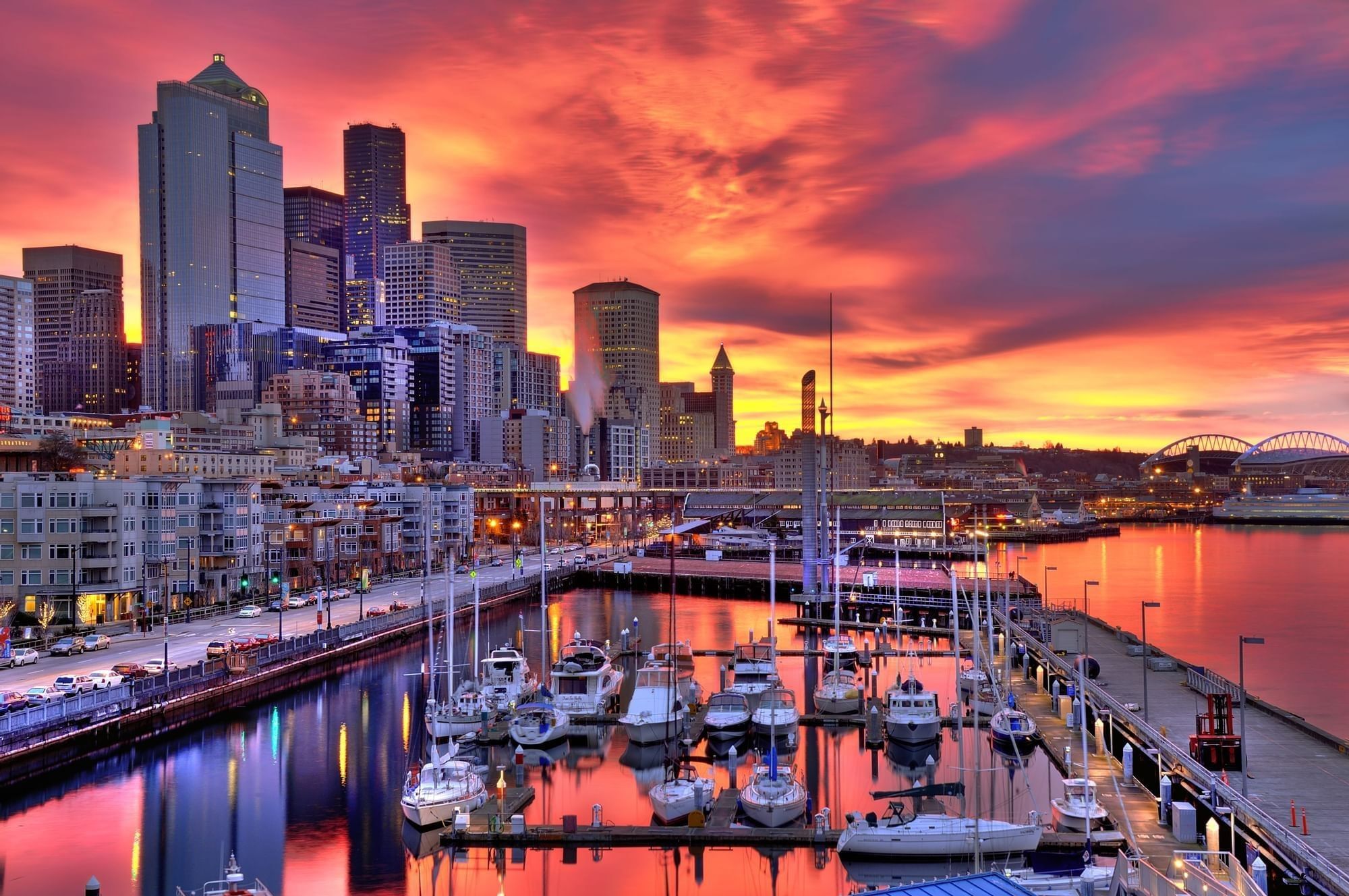 A city skyline at sunset with a marina in the foreground.