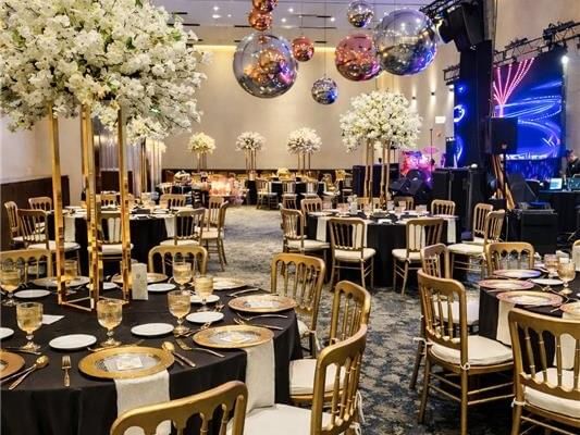 Decorated banquet hall with tables, chairs, floral centerpieces, and disco balls at Live Aqua Monterrey.