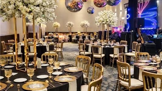 Decorated banquet hall with tables, chairs, floral centerpieces, and disco balls at Live Aqua Monterrey.