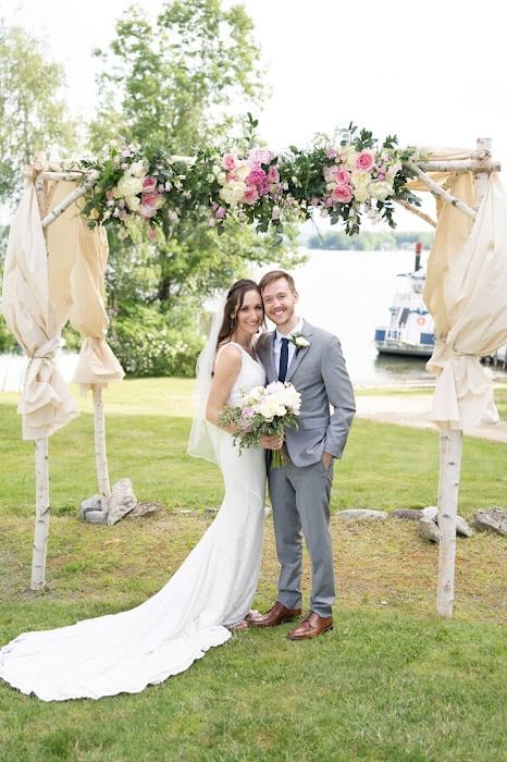 Newlyweds posing by the wedding arch at Wolfeboro Inn