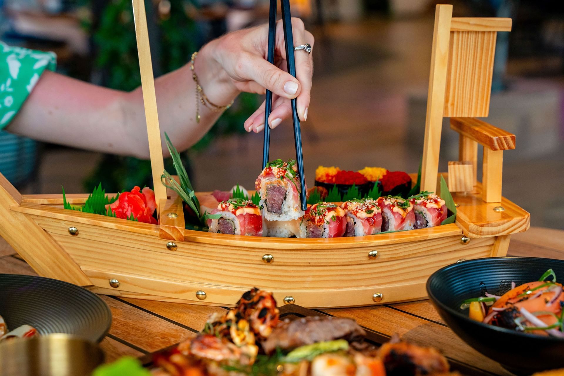 Hand-picking sushi with chopsticks from a decorative sushi boat at Bobbie\'s Beach Club at Golden Rock Resort
