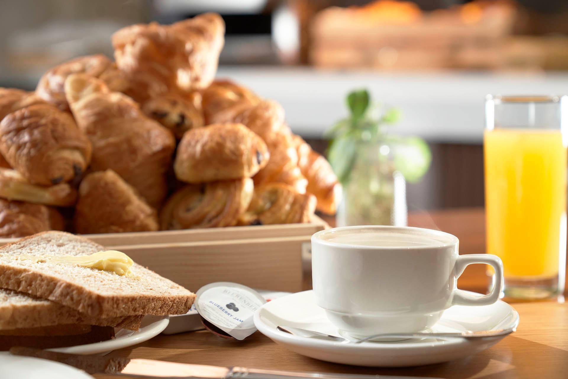 Image 6: Cozy breakfast buffet at Orchard Grand Court with coffee, bread, croissants, and a glass of orange juice