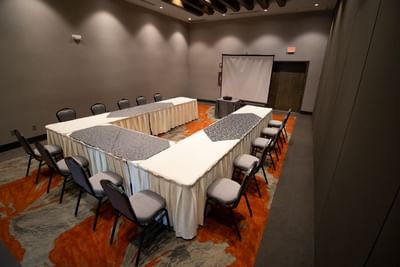 U-shaped table set up facing the projector screen in Araiza Hall at Hotel Mirra