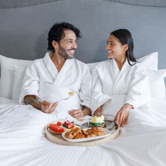 Couple having breakfast on the bed in Park Suite at Pullman Sydney Hyde Park