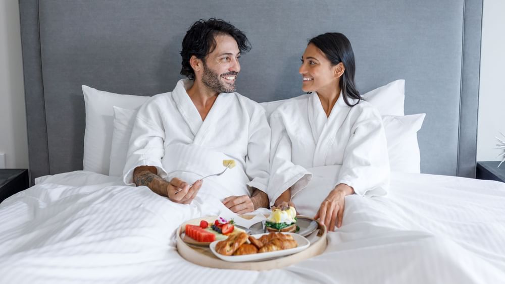 Couple having breakfast on the bed in Park Suite at Pullman Sydney Hyde Park