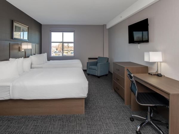 Room with two queen beds, desk, chair, and TV.