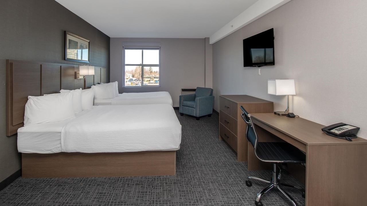 Room with two queen beds, desk, chair, and TV.