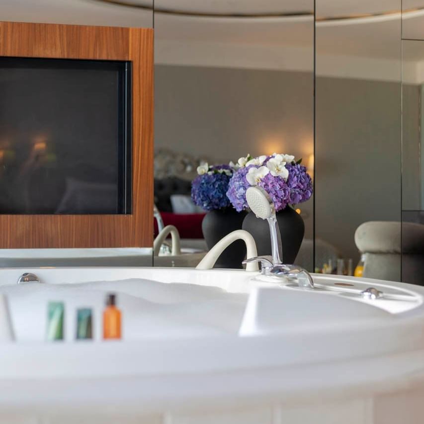 Bathroom interior with a bathtub, TV stand and toiletries at CVK Hotels