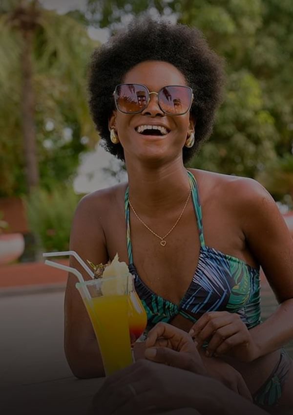 Woman in a swimsuit holding a cocktail outdoors at Azalai Hotel Ouagadougou