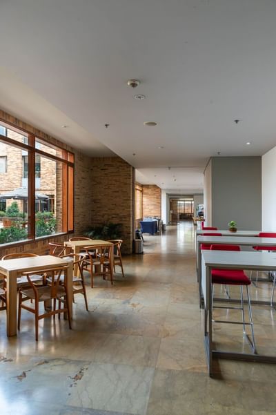 A bright lounge area at Habitel Hotel Select with tables, chairs and large windows looking out onto a patio