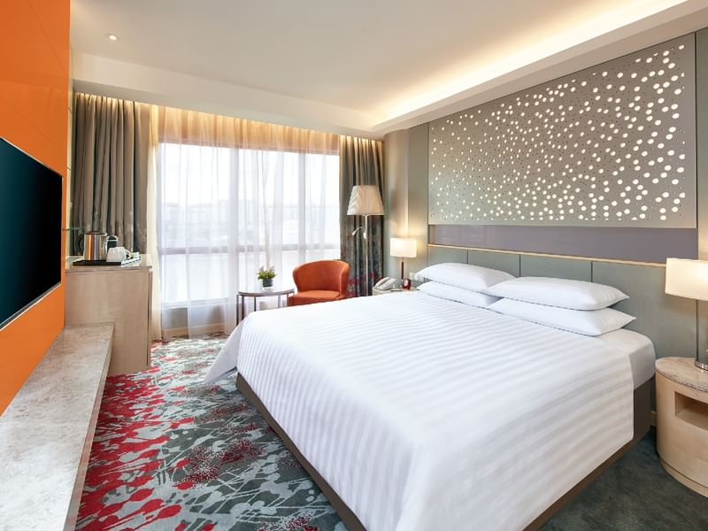 A modern Deluxe King Room at Sunway Hotel Pyramid, featuring a king bed, vibrant carpet, and city views