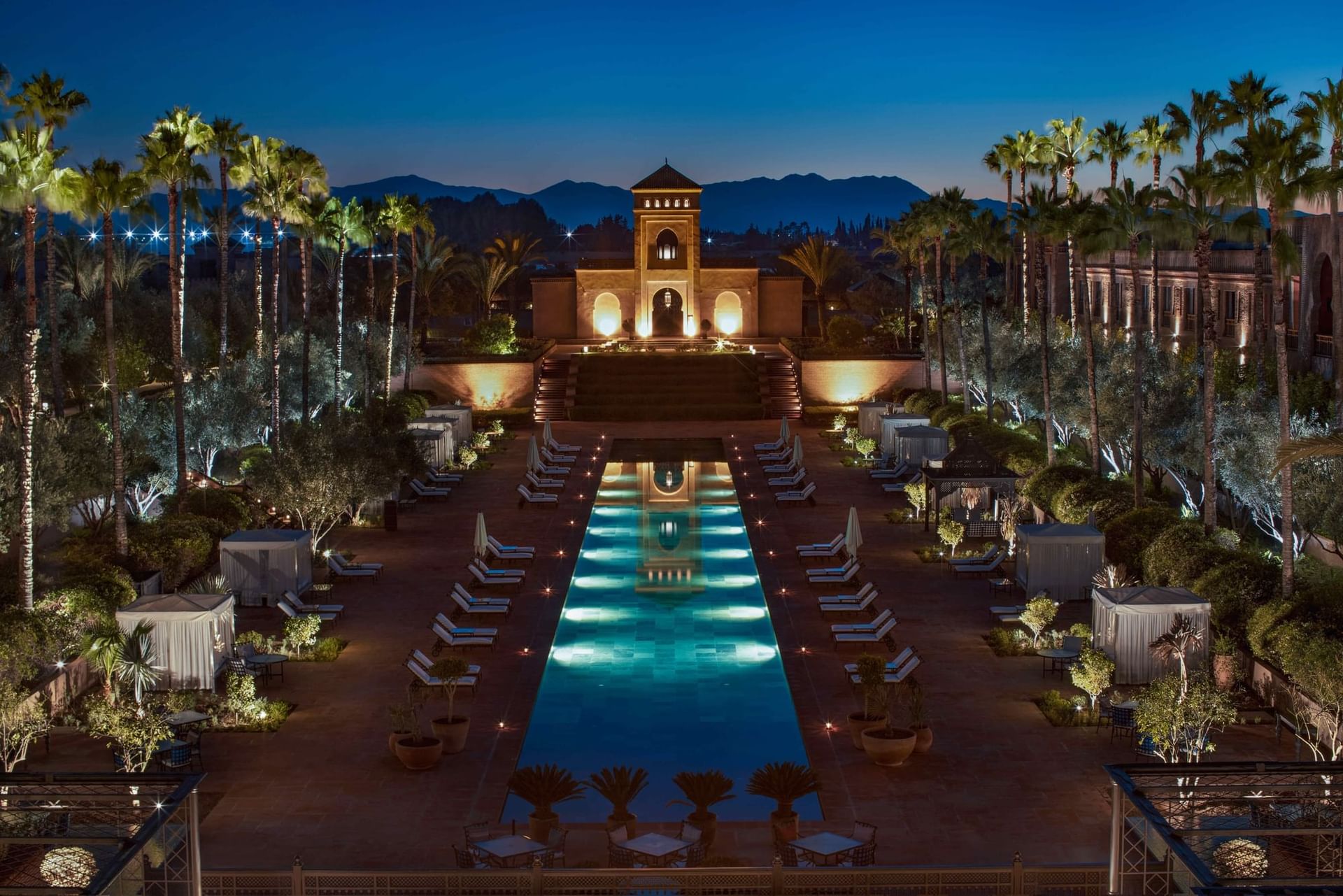 Outdoor swimming pool with a garden view & sunbeds at night, Selman Marrakech