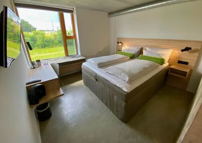 Workdesk facing bed by the window with seating in the Deluxe Double Room at Avaneo Hotel, featuring sustainable hotel rooms