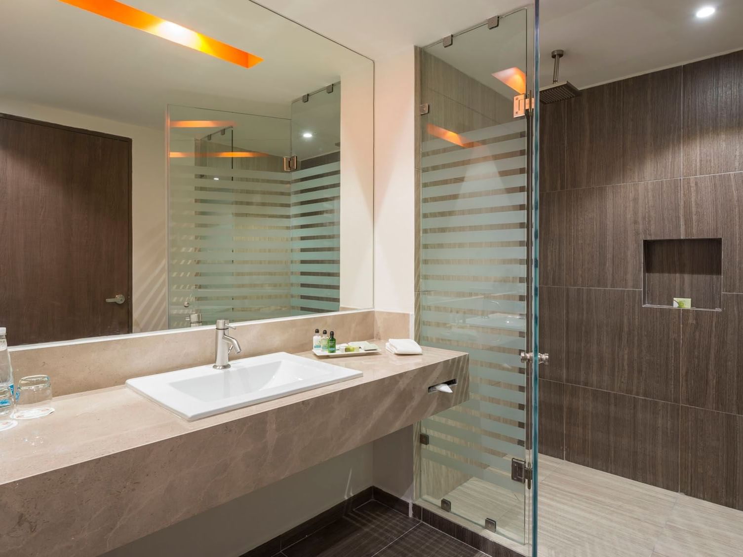 King Deluxe bathroom with a marble vanity, large mirror, and a sleek glass-door walk-in shower at Real Inn Celaya
