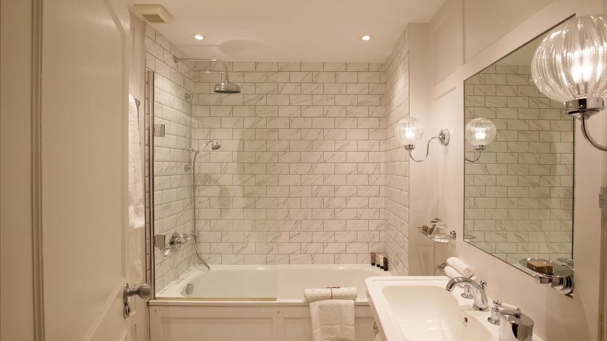 Two-bedroom apartment bathroom with mirror and bathtub at The Capital Hotel, Apartments and Townhouse
