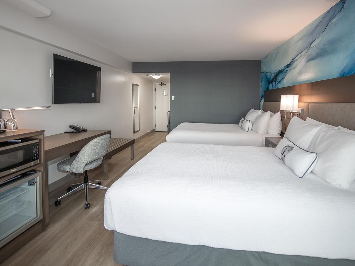 Two queen beds with amenities and a desk in a room at Coast Bastion Hotel in Nanaimo.