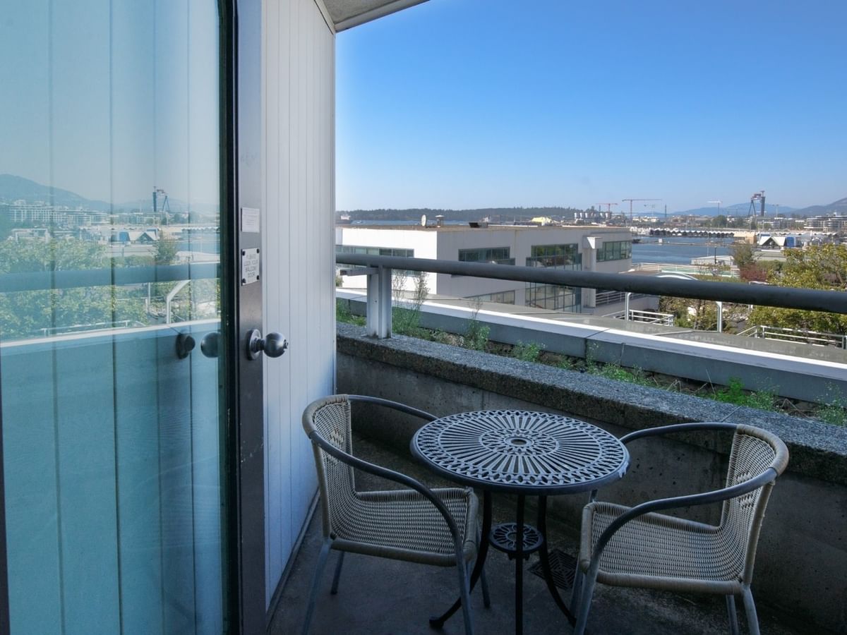 Coast Premium King with Patio room, balcony with two chairs and a table overlooking the city at Coast Lonsdale Quay Hotel