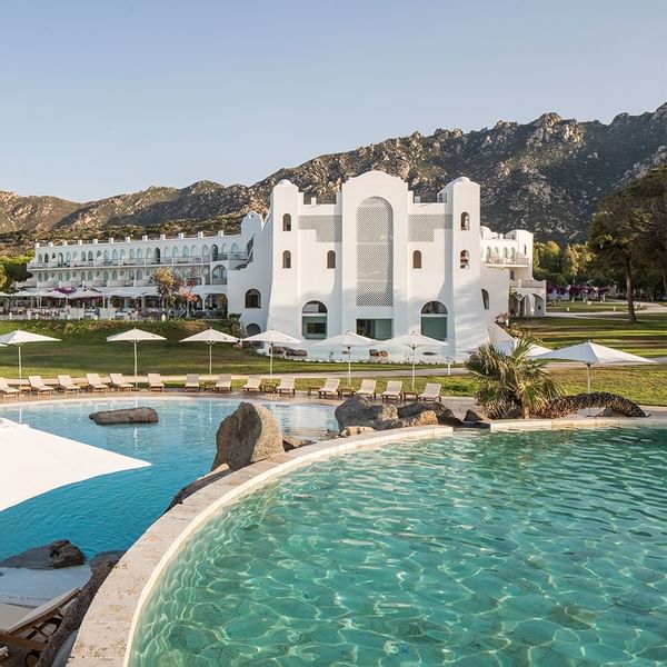 Pool with hotel exterior at Falkensteiner Hotel Capo Boi