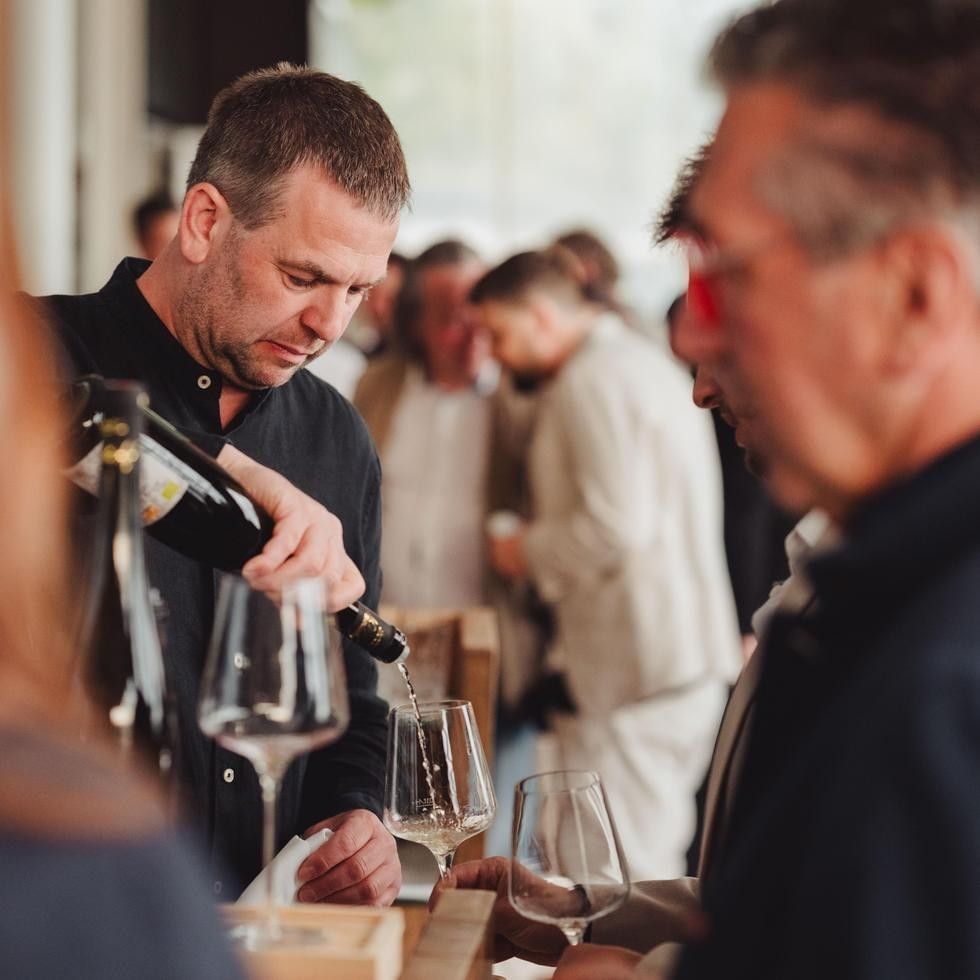 Man pouring wine into glasses at Mountain Wine Festival.