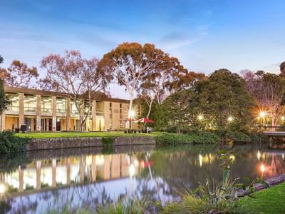 La Trobe University Glenn College building by a serene pond at dusk.