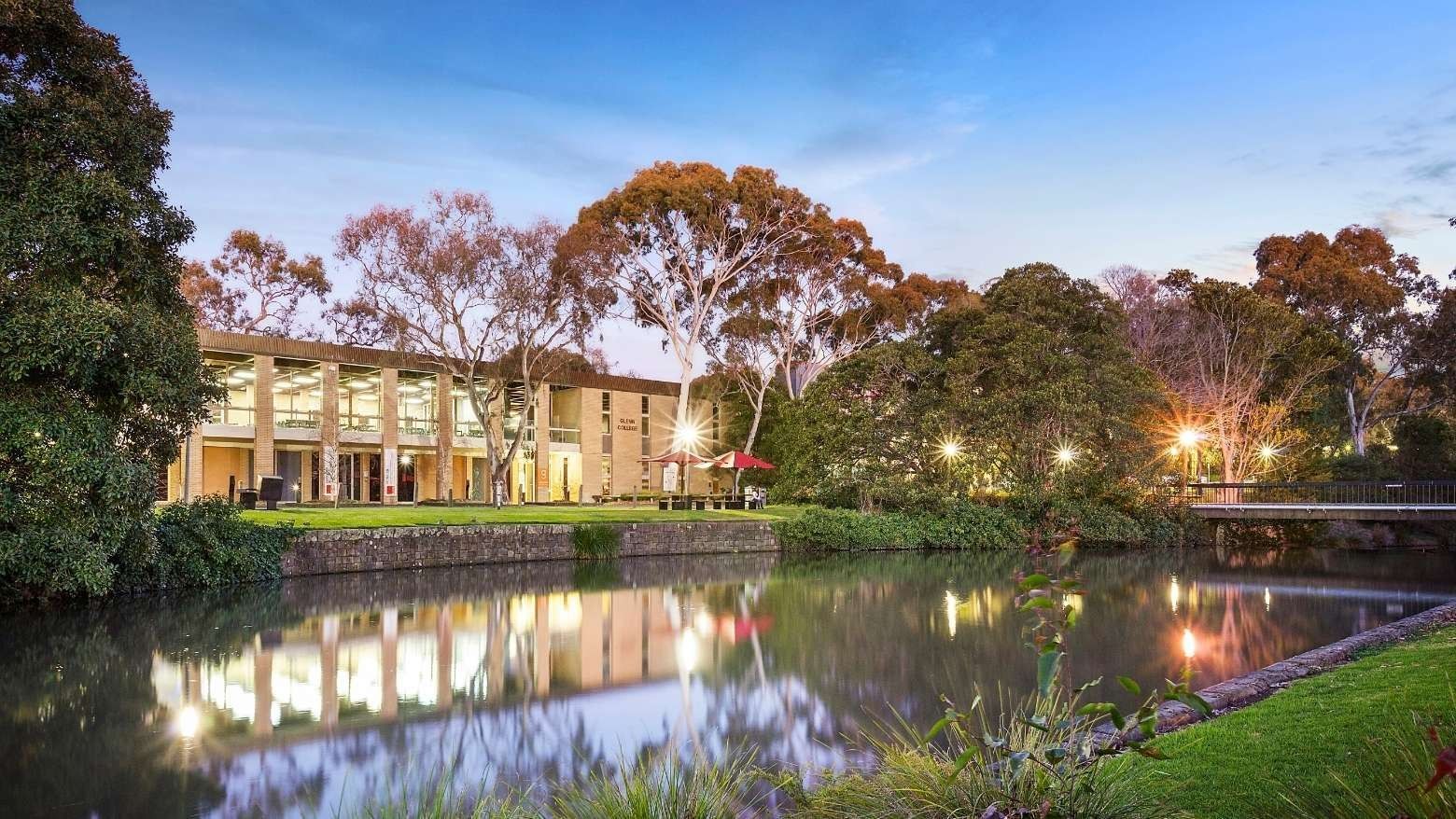 La Trobe University Glenn College building by a serene pond at dusk.