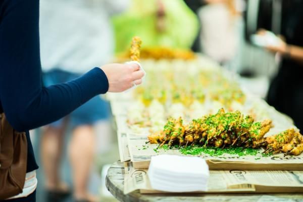 Women picking up chicken skewer to put into container in an effort to make the most of leftovers at event