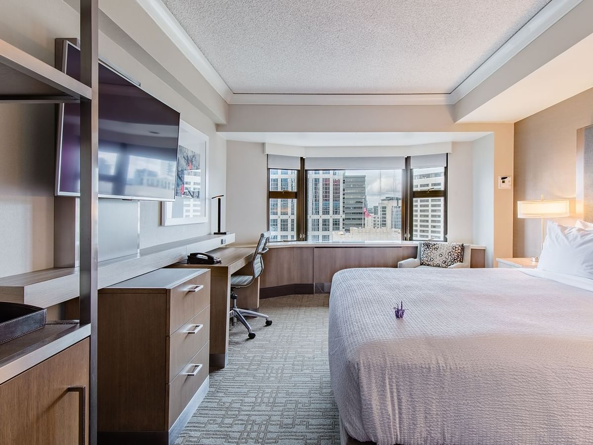 Hotel guestroom with king bed, work desk, TV and a skyline view