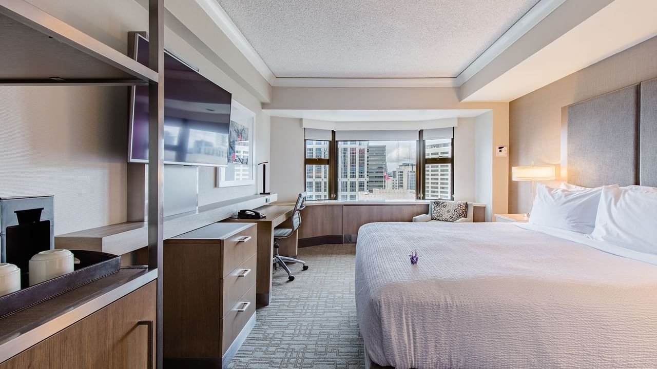 Hotel guestroom with king bed, work desk, TV and a skyline view