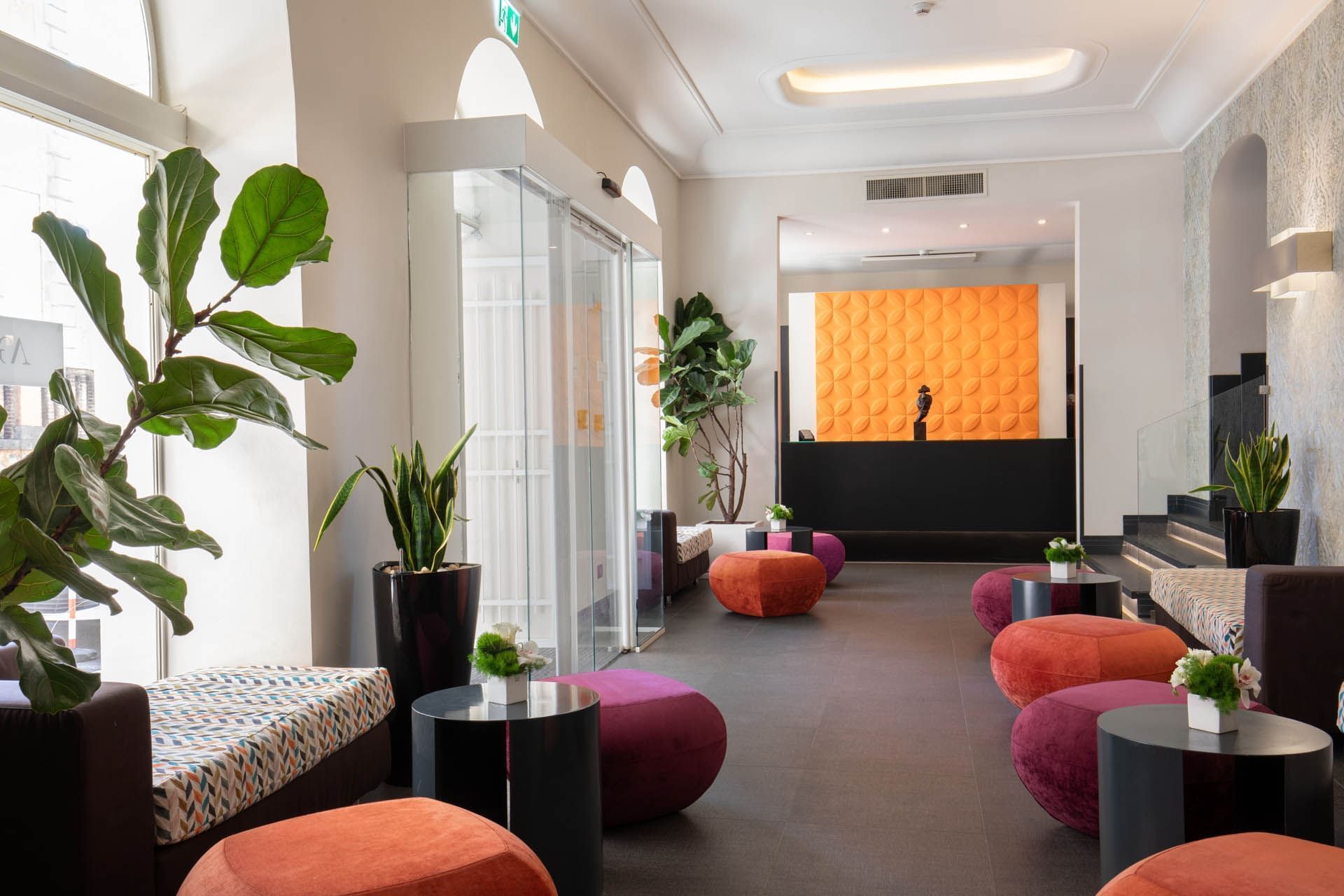 The Republic Hotel lobby featuring colorful seating, plants, and an orange accent wall behind the reception desk.