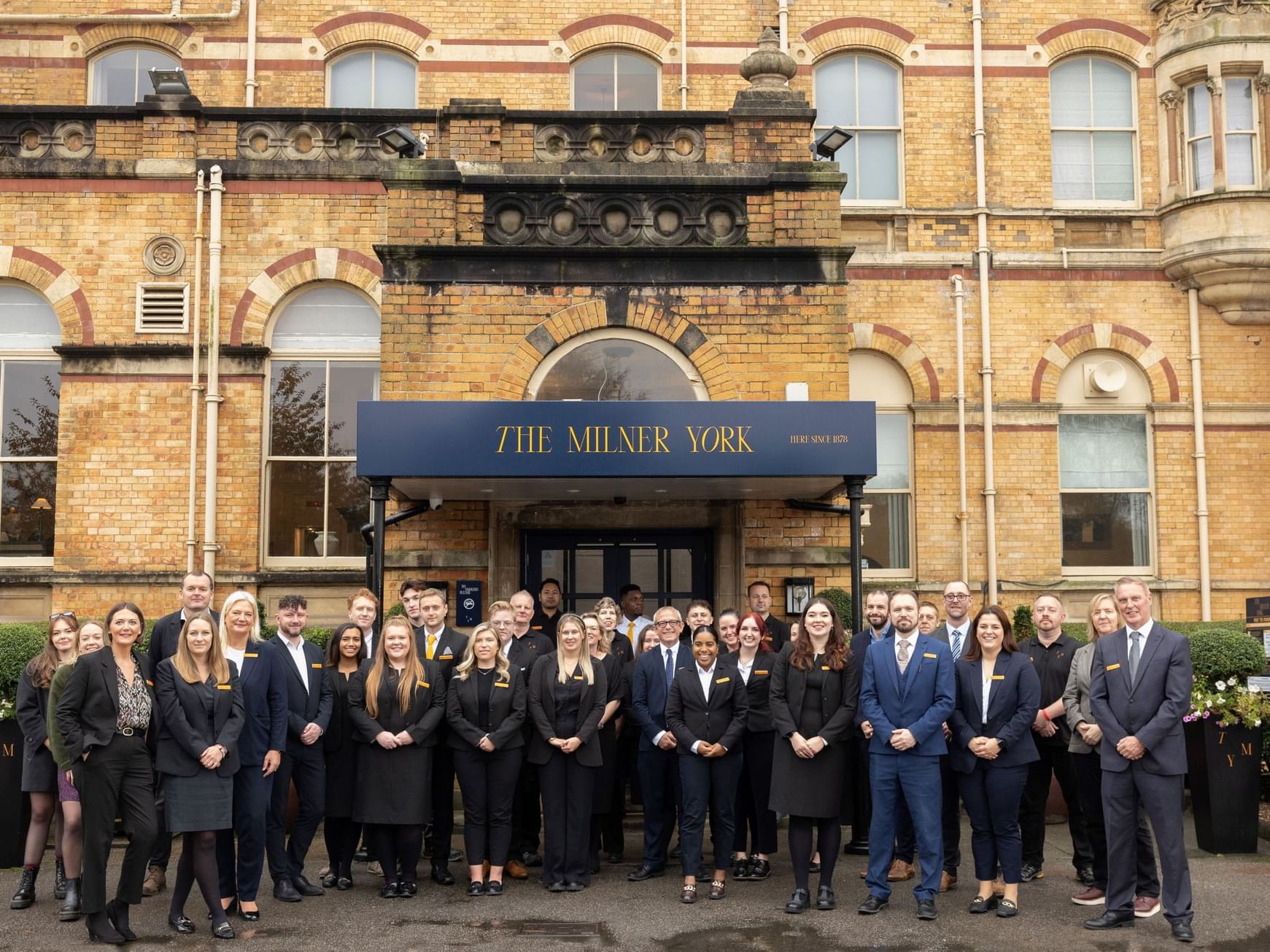 Group of people in formal attire standing in front of The Milner York hotel