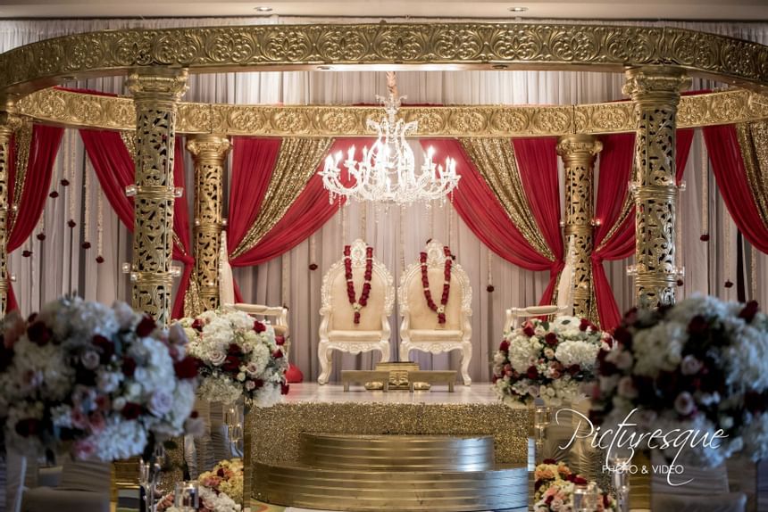 indian wedding altar with white chairs and red curtain draping