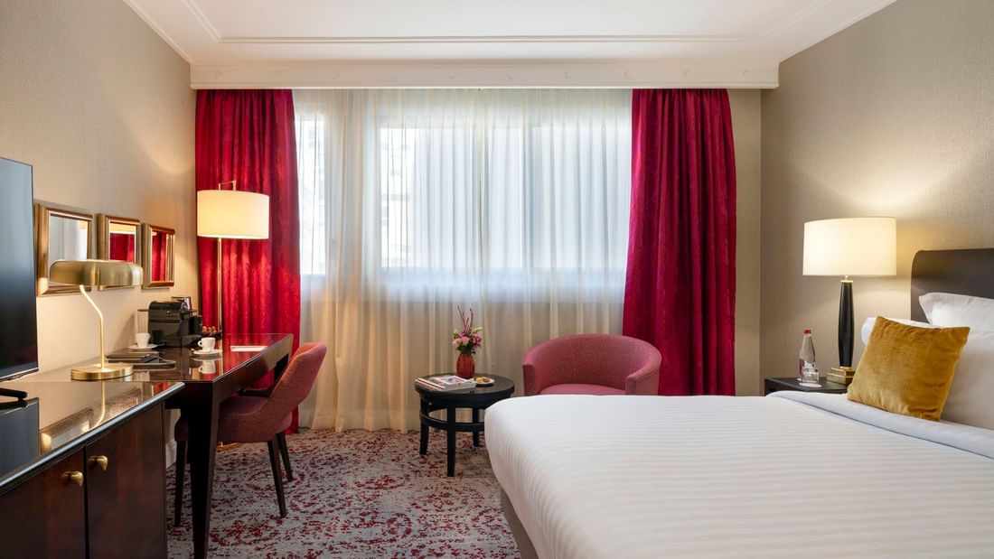 Workspace with a desk by an armchair surrounding a small coffee table in Superior Room at Warwick Paris Champs Elysées