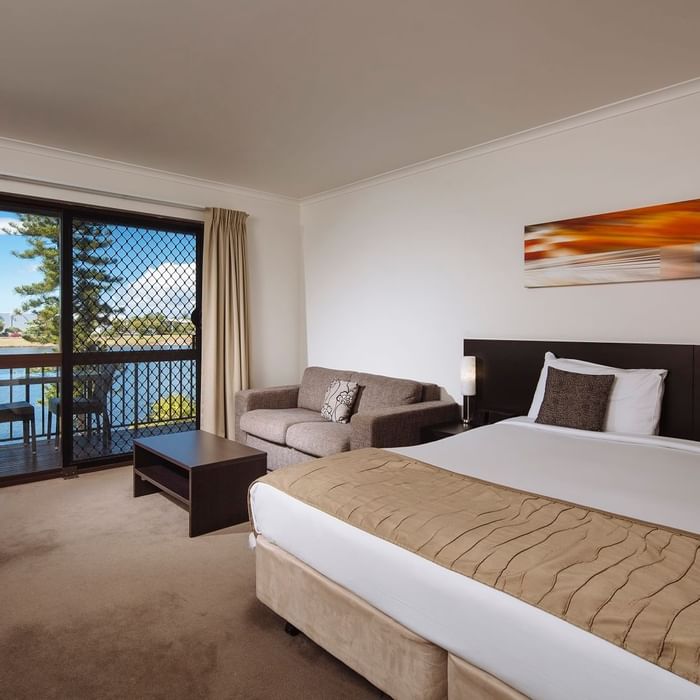 Deluxe Room with a king bed, sofa, and balcony view, featuring modern decor at Mercure Hotel Townsville