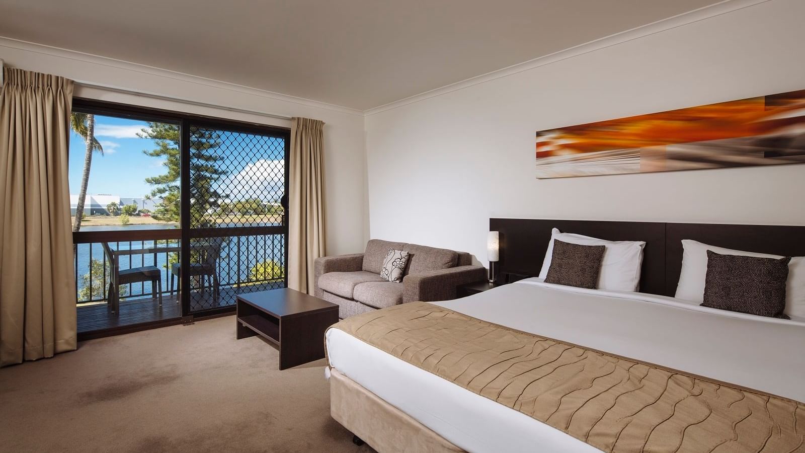 Deluxe Room with a king bed, sofa, and balcony view, featuring modern decor at Mercure Hotel Townsville