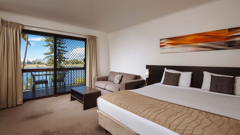 Deluxe Room featuring a king bed, sofa, table, and large windows with views of water outside at Mercure Hotel Townsville