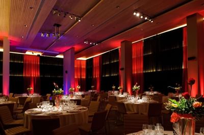 Mesas de banquete con decoración floral bajo focos rojos en Salón Mayo en NOI Vitacura, Santiago, Chile