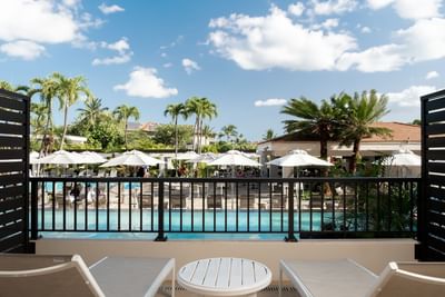 Inviting patio with two lounge chairs and a table, overlooking a swimming pool at the Maui Coast Hotel