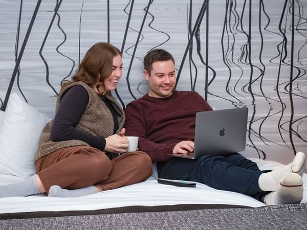 Couple sitting on a bed with a laptop.