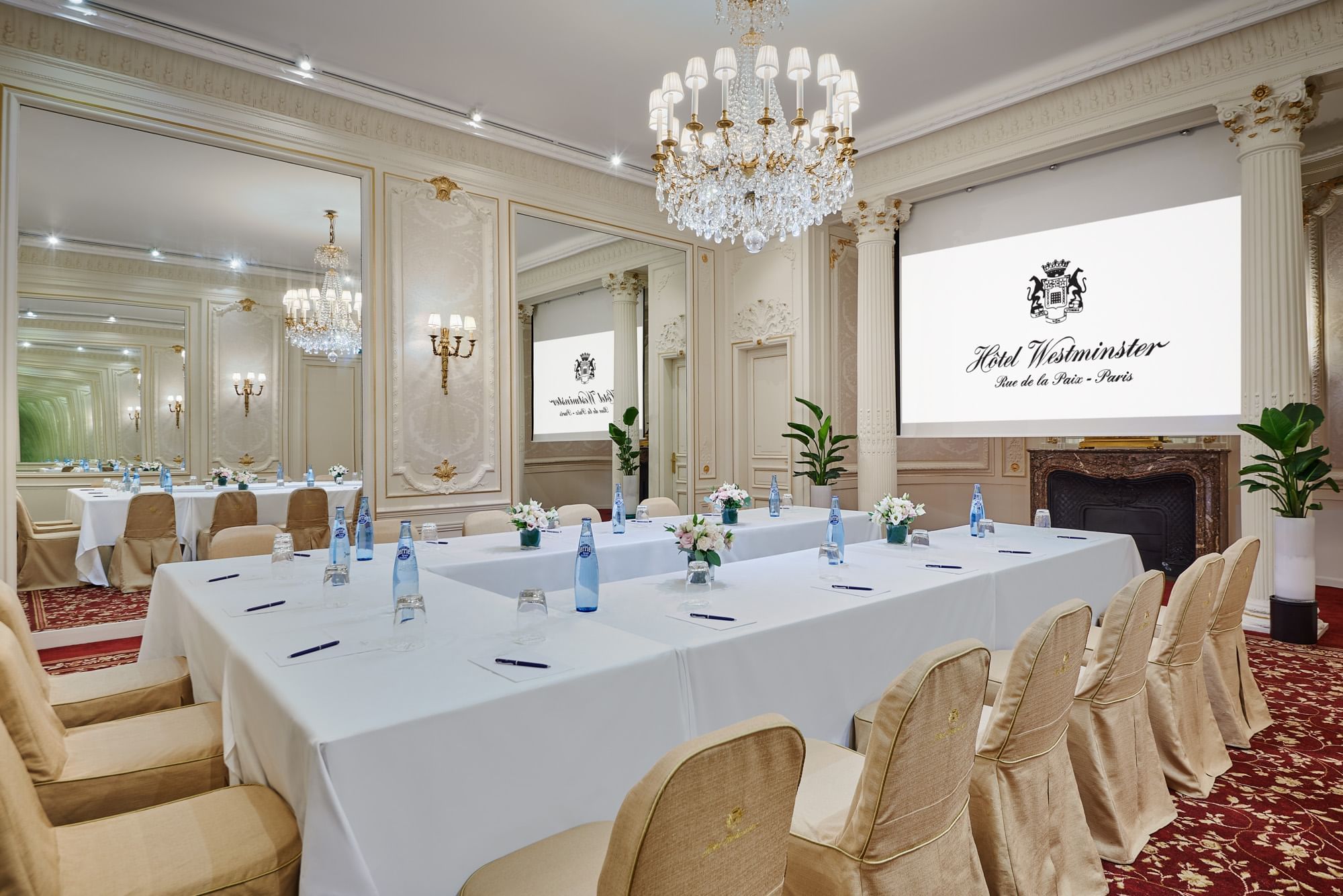 Interior of Capucines meeting room with U-shaped table set up, projector screen and a chandelier at Hôtel Westminster - Paris