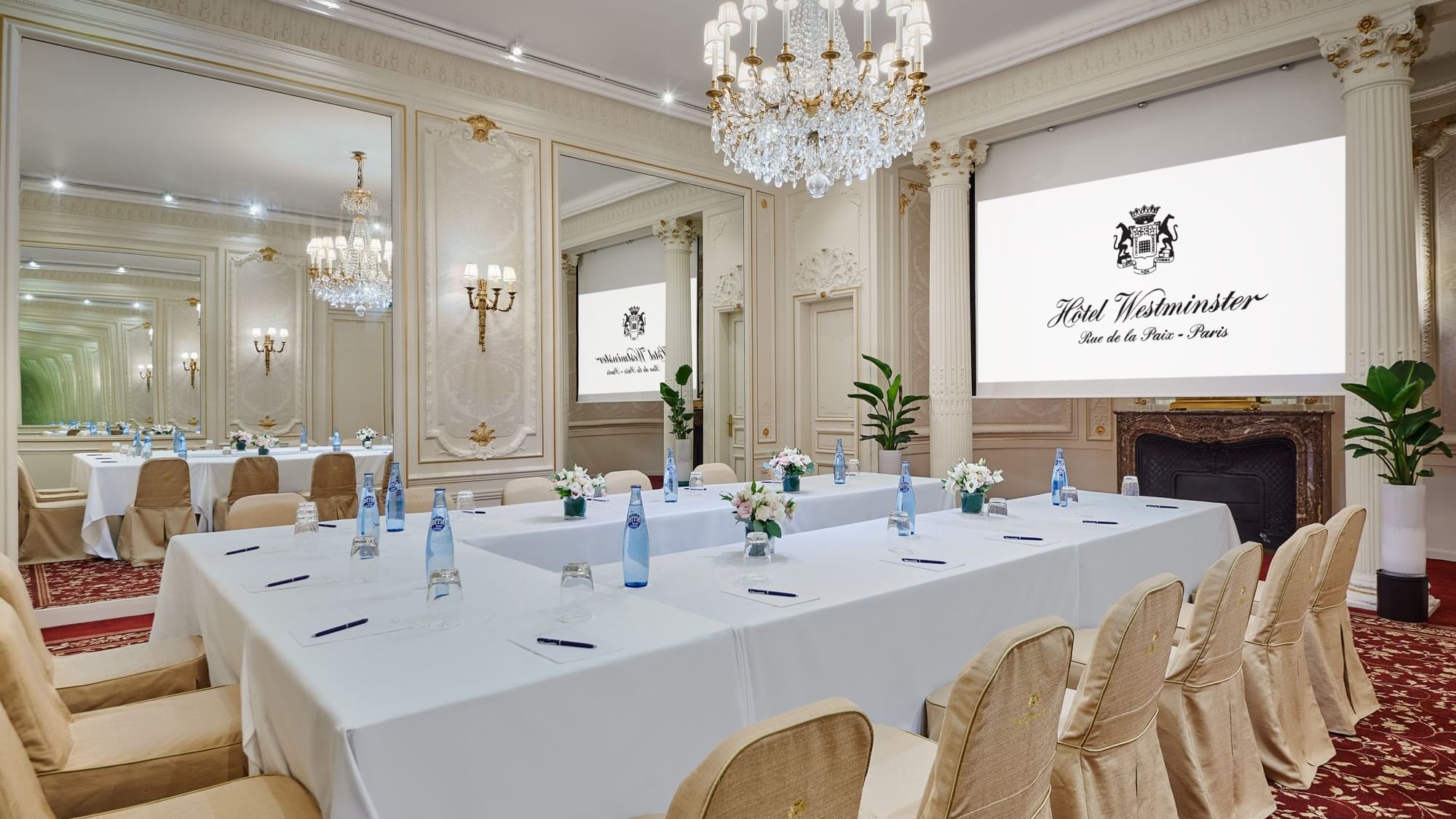 Interior of Capucines meeting room with U-shaped table set up, projector screen and a chandelier at Hôtel Westminster - Paris