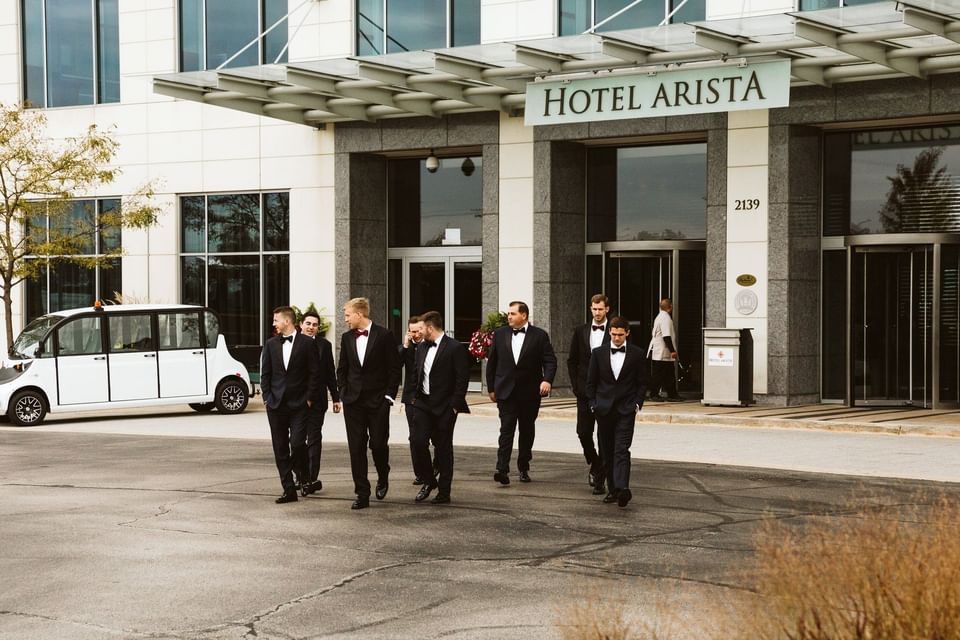 a group of men in tuxes walking across a street