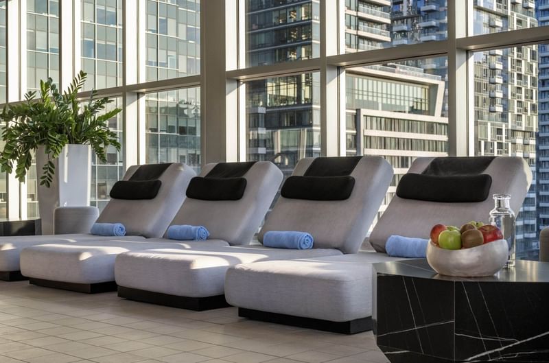 Quatre chaises longues avec oreillers et serviettes, fruits dans un bol à Warwick Le Crystal Montréal