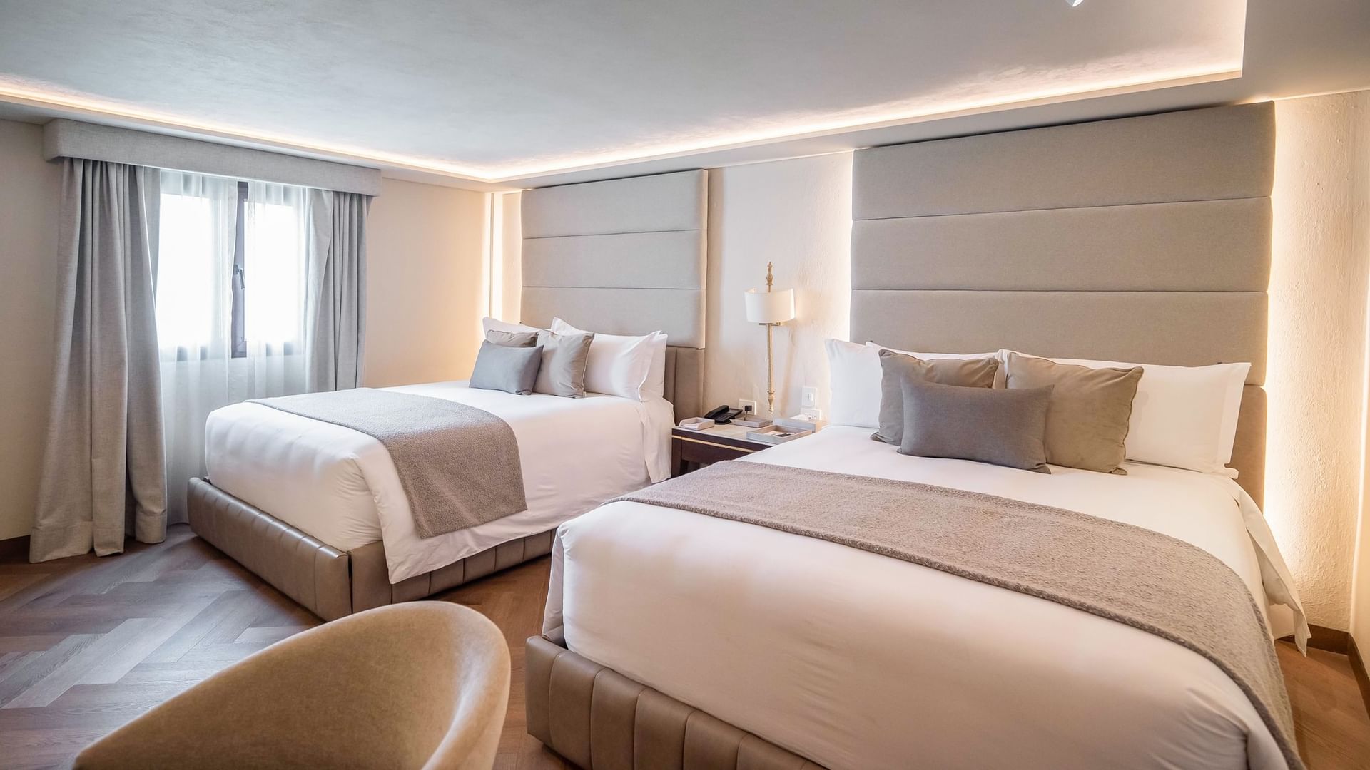 Dos camas dobles con ropa de cama elegante en la habitación New Class del hotel Quinta Real Puebla en Heroica Puebla de Zaragoza.