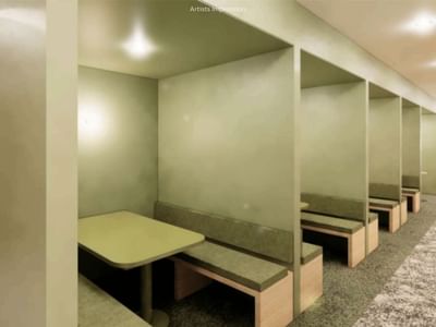 Man walking past a long row of green cubicles with tables and benches at UniLodge Brisbane City.