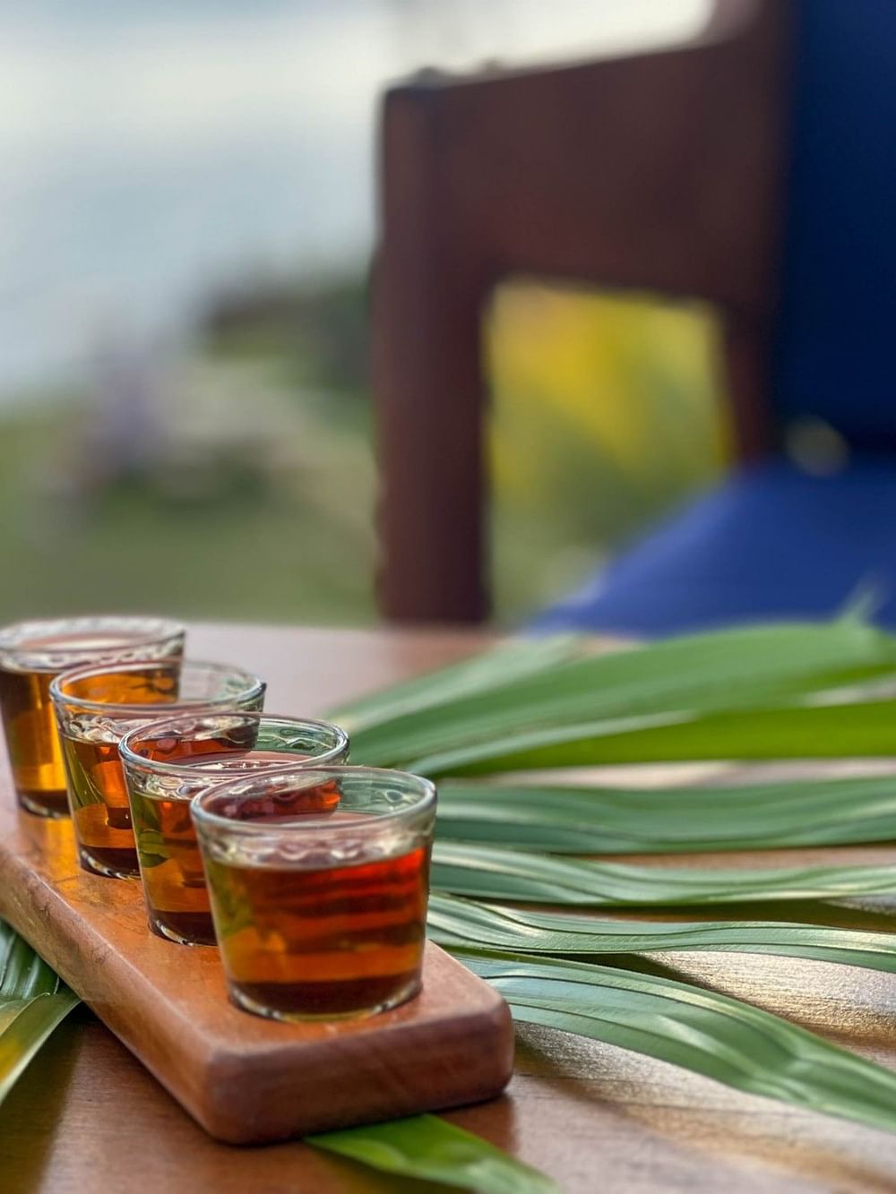 Four glasses of amber liquid on a wooden board with leaves at The Naviti Resort - Fiji, Korolevu.