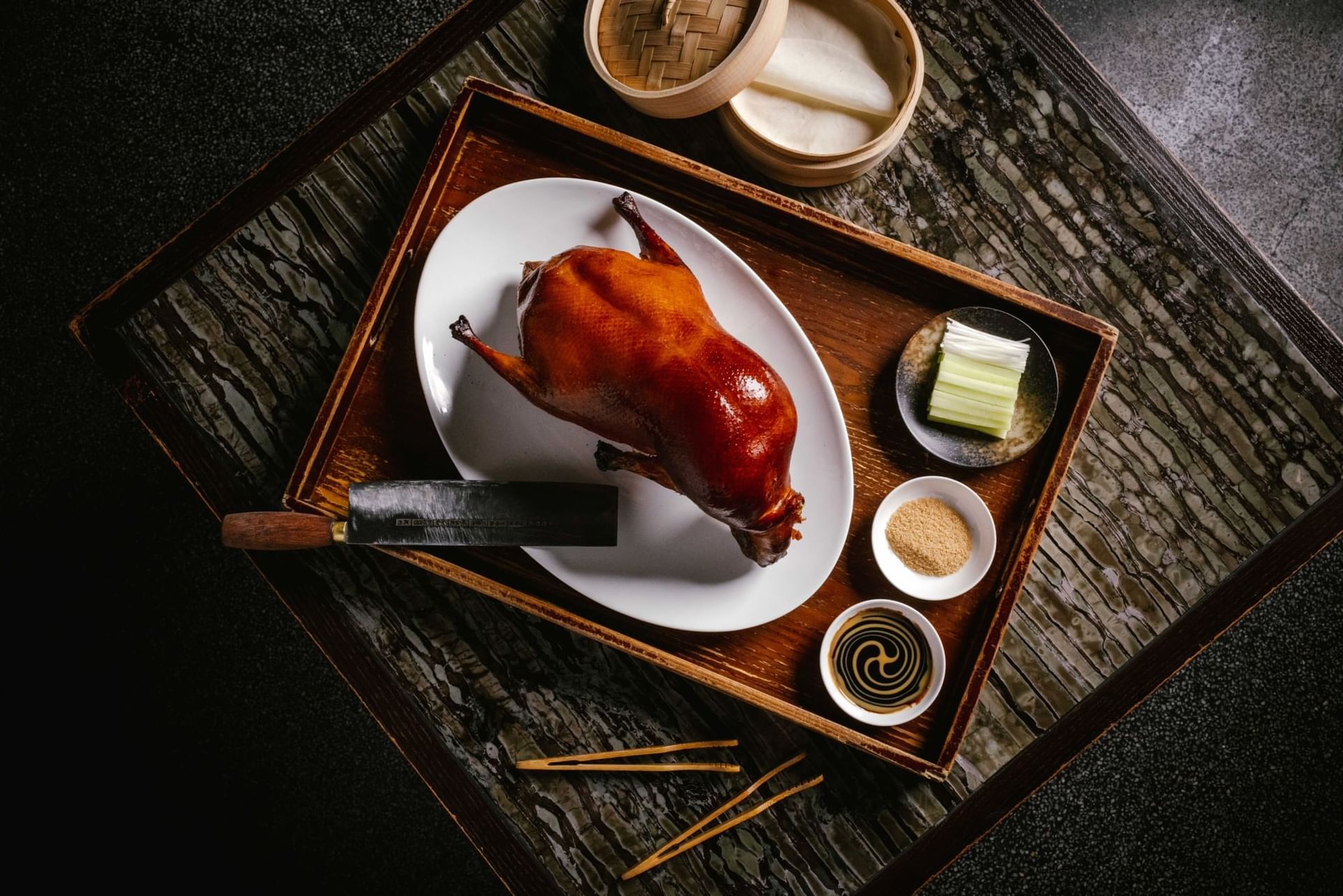 Paradox Hotel Vancouver Peking Roasted Duck on a white plate with side dishes and chopsticks.