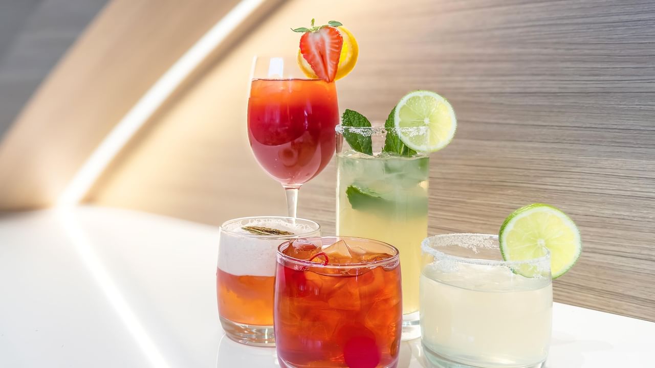 Colorful cocktails garnished with fresh fruit and mint.