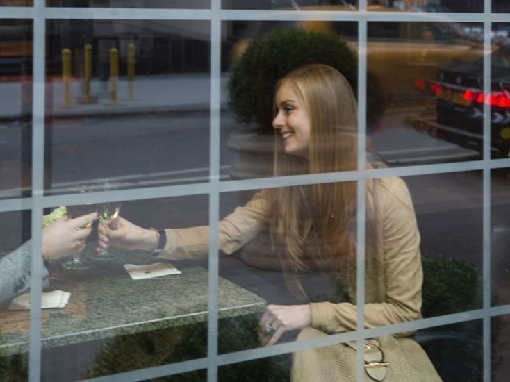 Smiling woman receiving room key at hotel reception desk viewed through window at Warwick New York